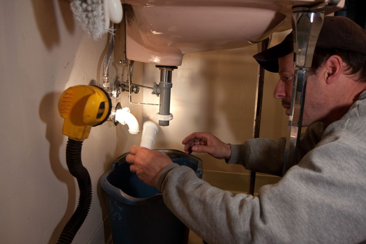 A plumber repairing pipes under a sink